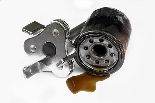 Old oil filter and engine tools on white background