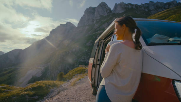 istock Thoughtful Female tourist Looking at Mountains While Leaning On Camper Van During Sunny Day 1877335715