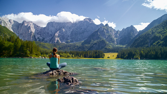 Capturing a Moment of Contemplation,a Rear View Reveals a Female Tourist Sitting on a Rock,Gazing at the Majestic Rocky Mountains. The Scene Unfolds by a Rippled Lake,Portraying the Traveler Immersed in the Awe-Inspiring Beauty of the Natural Landscape