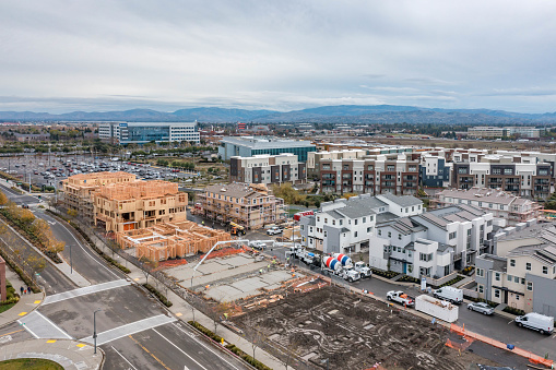 drone images of a new apartment building in Dublin, California with cement trucks, framing, construction workers surround by commercial and real estate