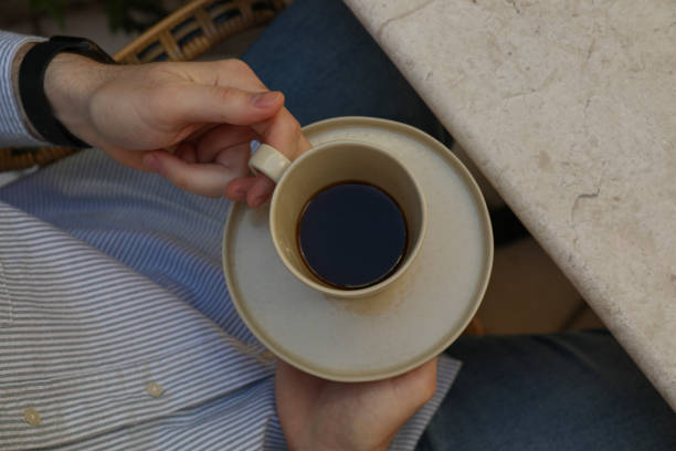 istock Cup with coffee and saucer in hands, top view 1877365290