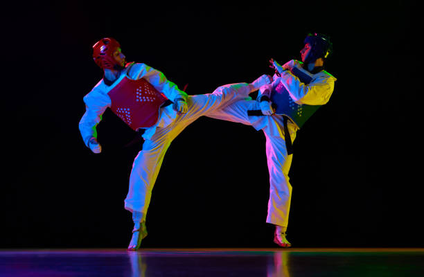 istock Competitive strong young men, taekwondo, karate athletes in motion, fighting, training against black background in neon light. Martial arts, combat sport 1877373622