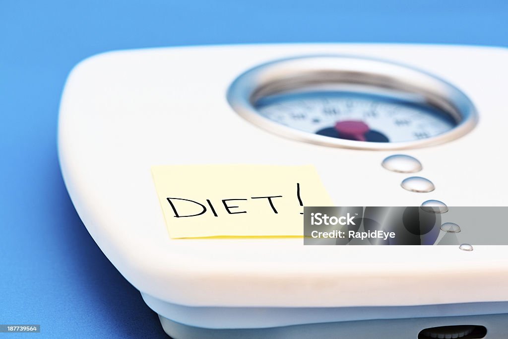 Bullying bathroom scales with reminder saying DIET! Nagging bathroom scales have a post-it label attached simply saying DIET! A stern reminder for the user or an example of someone with an obsession.  Adhesive Note Stock Photo