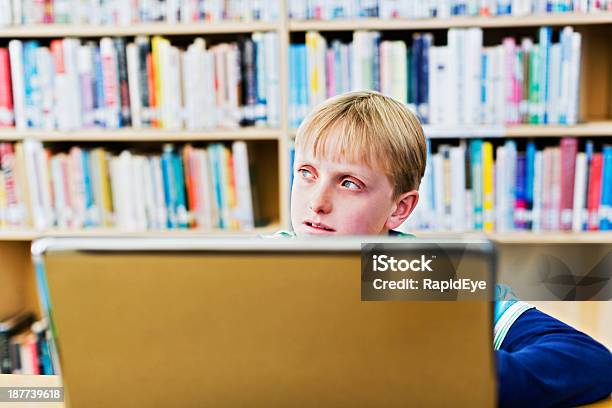 Blondes Elementary Schulkindnur Jungen Mit Laptop In Bibliothek Wird Abgelenkt Stockfoto und mehr Bilder von 10-11 Jahre