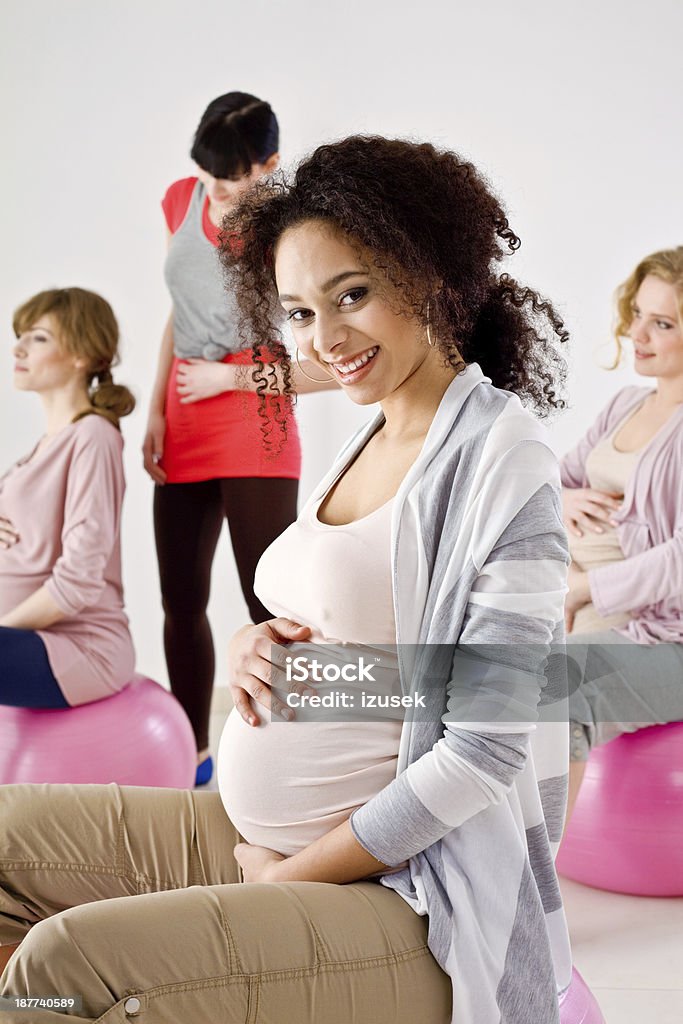 Pregnant women on gym balls Three preety, pregnant young adult women exercising on gym balls with their phisical trainer. Focus on the African American woman looking at camera and smiling. 20-24 Years Stock Photo