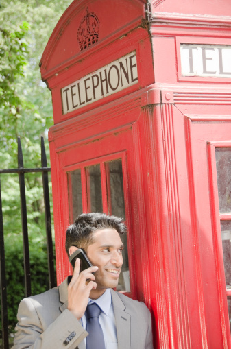 Smiling Indian businessman in London talking on the phone.