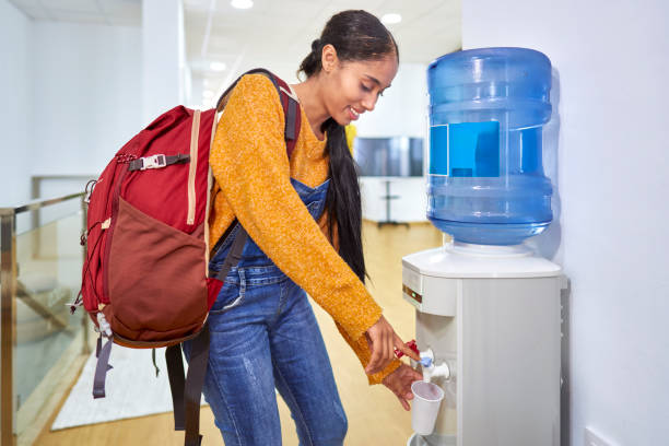 pretty Colombian Latin girl drinking water from the machine at the co working center taking a break