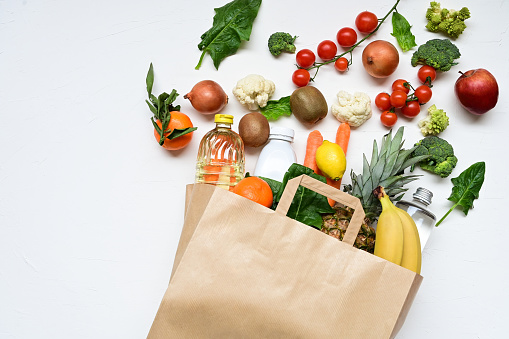 Paper bag full of groceries on a white background.
