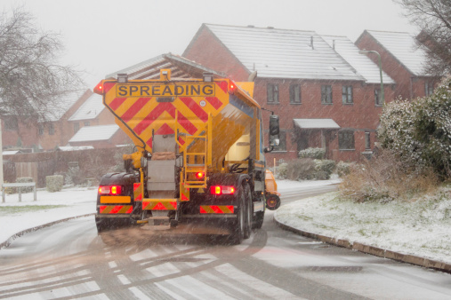 Gritter/snow plow clearing the residential streets of Shrewsbury Shropshire whilst a blizzard rages all around.