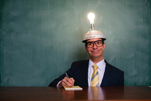 An adult businessman with a light bulb helmet is excited as he has the next big idea.