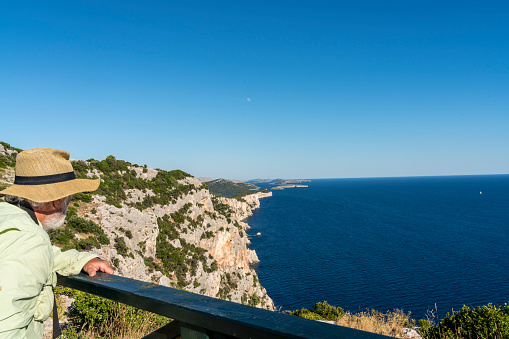 Man, side view, admiring the view of cliffs of Telascica, national park in Dugi otok island, Kornati islands in background. Croatia