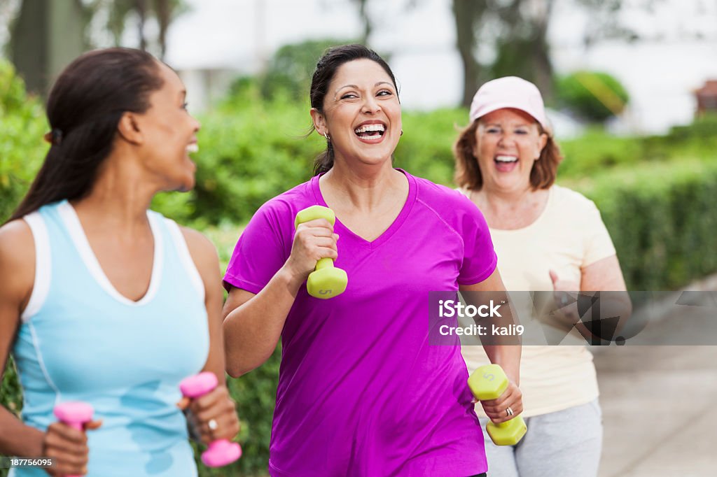 Women exercising in park Multi-ethnic women (30s, 40s, 60s) exercising in park, power walking.  Hispanic woman in middle (30s). Walking Stock Photo