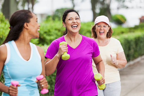 Women exercising in park Multi-ethnic women (30s, 40s, 60s) exercising in park, power walking.  Hispanic woman in middle (30s). dumbbell photos stock pictures, royalty-free photos & images