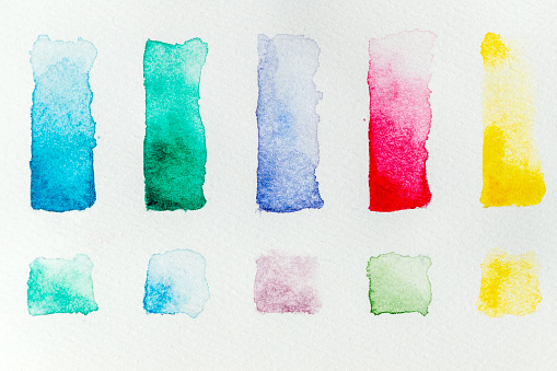 Watercolor paint swatches lined up in a grid on a white background, flat lay. High quality photo.