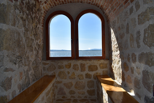 Inner part of a fortress with stone walls and wooden benches. Beautiful view through the window in a fort.