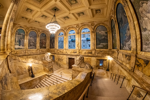 The Grand Staircase takes visitors from the lobby to the second floor Bates Reading Room and other galleries. The lion sculptures represent the two Massachusetts volunteer infantry regiments of the Civil War. The sculptures are by Louis Saint-Gaudens,. The murals in the blind arches are by Pierre Puvis de Chavannes, whom many consider one of the great muralists of the 19th century.