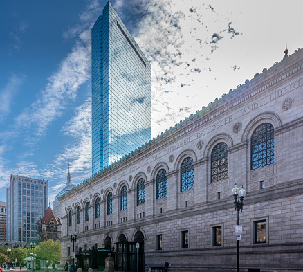 The Boylston Street facade of the Boston Public Library’s McKim Building is featured here. John Hancock Tower rises behind the library, and just to the left of that, the old John Hancock Building.