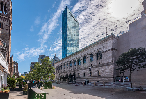 The Boylston Street facade of the Boston Public Library’s McKim Building is featured here. John Hancock Tower rises behind the library, and just to the left of that, the old John Hancock Building. The campanile of Old South Church is on the left side.