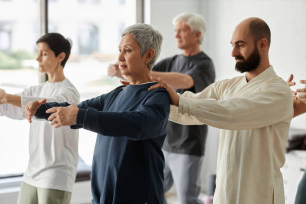 istock Trainer Assisting Senior Woman during Qigong Exercise 1877662495