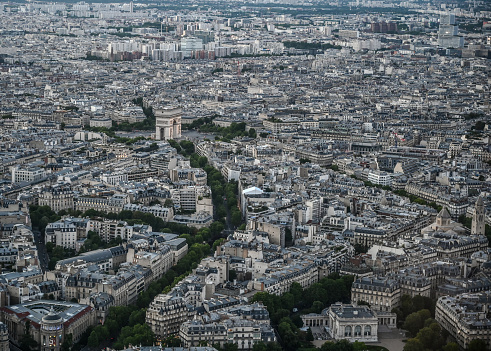 Paris, France, June 2022. Amazing golden hour photo with pov from the top of the Eiffel Tower. In evidence the triumphal arch, some cars have the lights on.