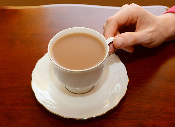 istock Woman picking up cup of tea from a table 187769327