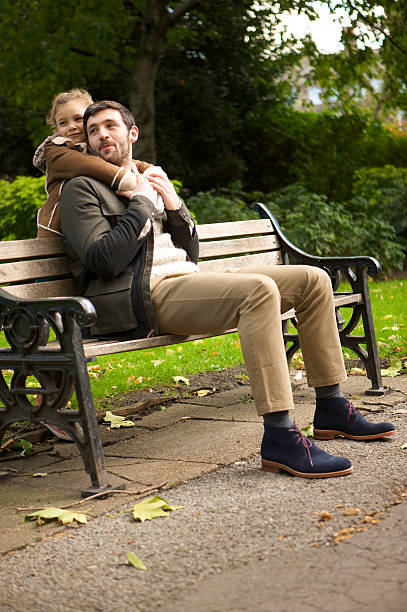 istock Father sitting on park bench as his daughter hugs him 187772984