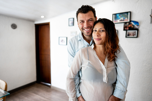 Portrait of a pregnant couple embracing at home