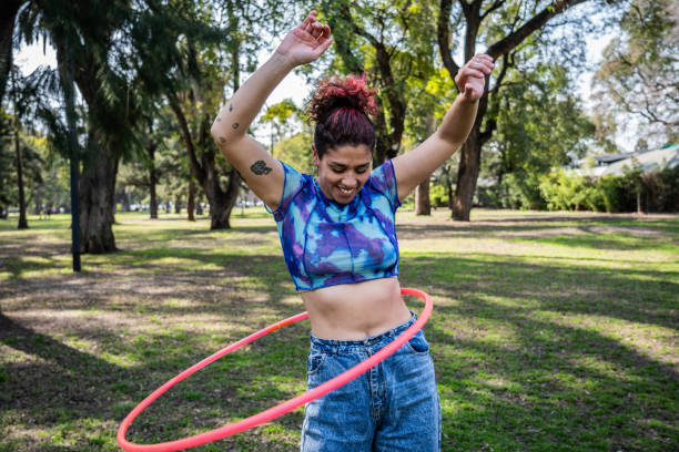 Young woman having fun with plastic hoop at the park