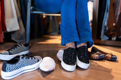 Low section of a woman trying on shoes in a thrift store