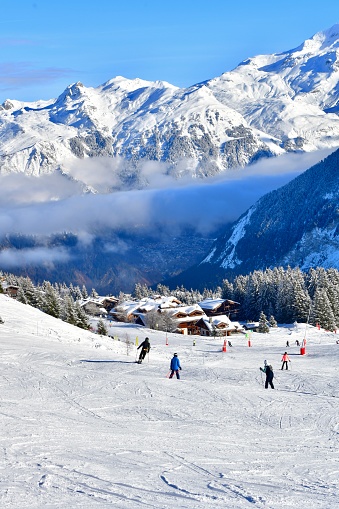 People skiing on the slopes of Courchevel ski resort with Mont Blanc mountain behind.