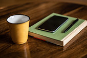 Phone, pen, diary and coffee on a wooden desk