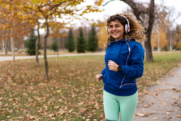 istock Young woman running in autumn park 1877829186
