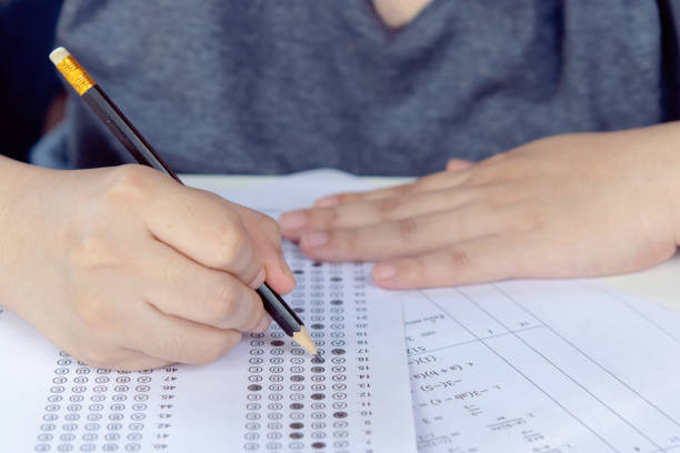 istock Students hand holding pencil writing selected choice on answer sheets and Mathematics question sheets. students testing doing examination. school exam 1877831262