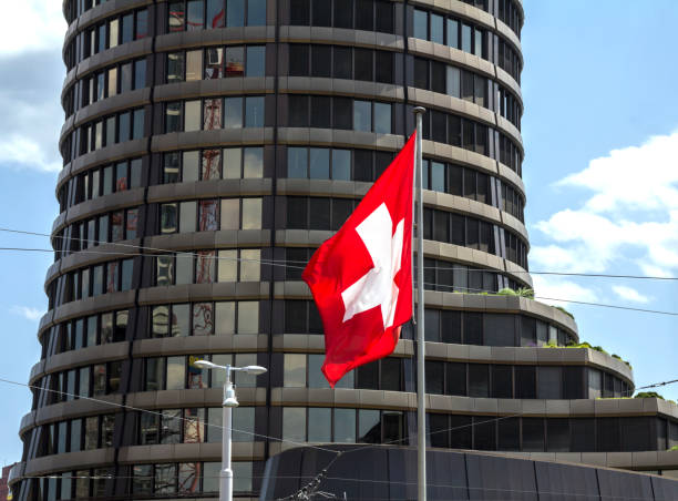 Swiss flag hanging from a pole on a building facade, Traditional buildings with tiled roofs and blue and white Lucerne flag on background,