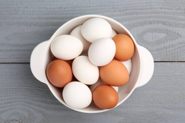 istock Unpeeled boiled eggs in saucepan on grey wooden table, top view 1877866946