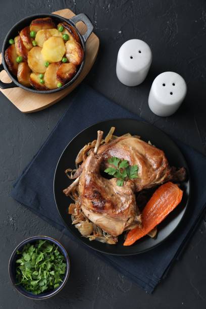 istock Tasty cooked rabbit meat with vegetables and potato served on black table, flat lay 1877868512