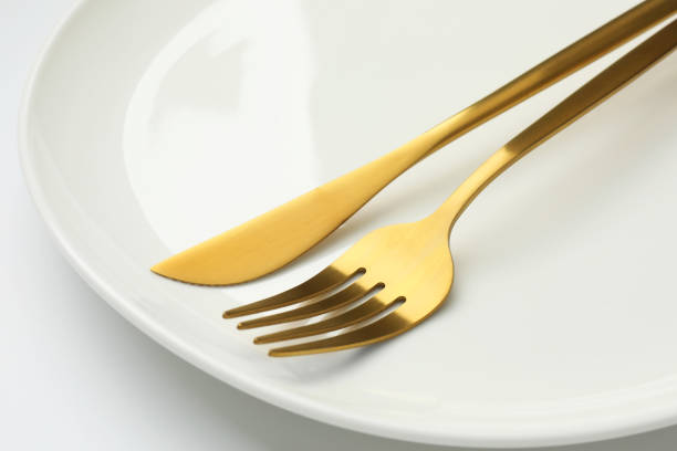 istock Clean plate, fork and knife on white background, closeup 1877879340