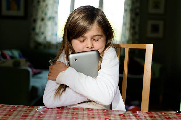 Hugging the tablet computer A young girl hugs her tablet computer hard. one girl only stock pictures, royalty-free photos & images