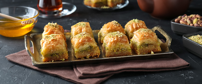 Delicious fresh baklava with chopped nuts served on grey textured table, closeup. Eastern sweets