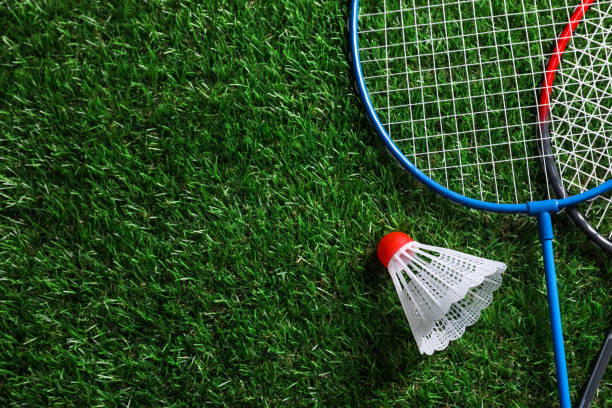 istock Two badminton rackets and shuttlecock on green grass, top view with space for text 1877959326