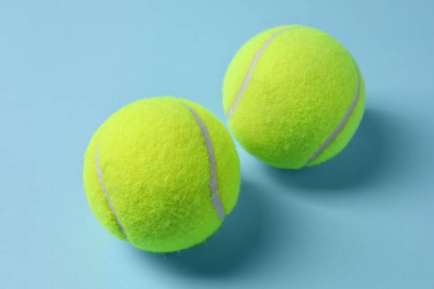 istock Two tennis balls on light blue background, closeup 1877960723