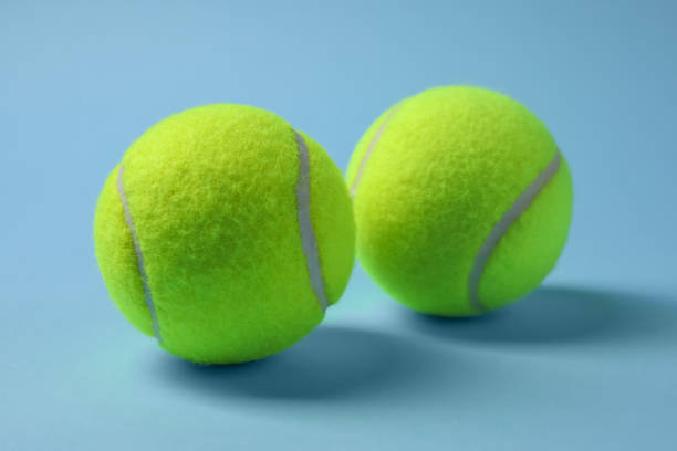 istock Two tennis balls on light blue background, closeup 1877972164