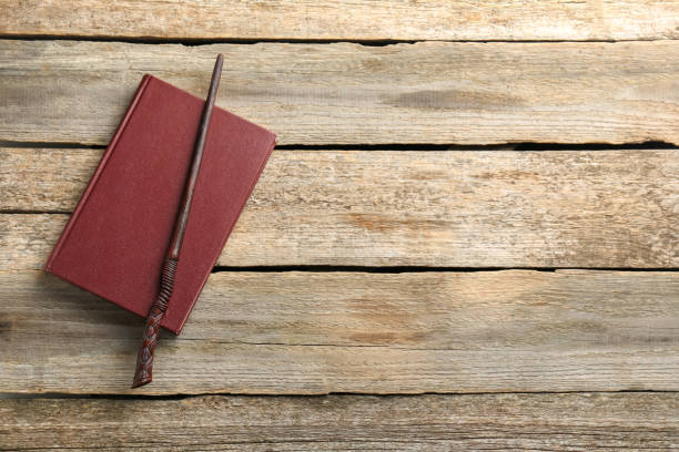 istock Old magic wand and book on wooden table, top view. Space for text 1877973724