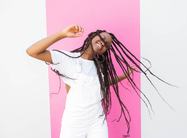 istock Girl with long braids having fun and dancing at a wall with pink stripe 1877989508