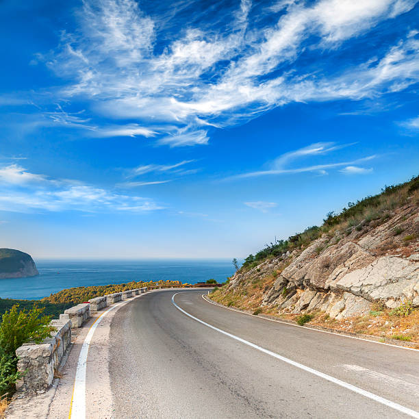 Turn of mountain highway with dramatic blue sky and sea on a background