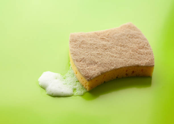 Cleaning sponge and a soapy foam on a light green background. Cleaning concept, cleaning service.Top view