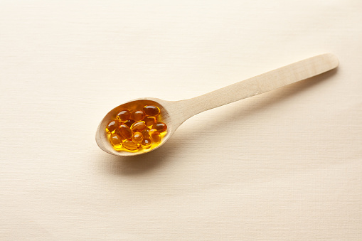 vitamin D3 capsules in a wooden spoon