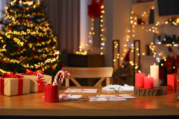 istock Santa's Claus workplace. Gift boxes, letters and candy canes on table in room with Christmas decor 1878033652