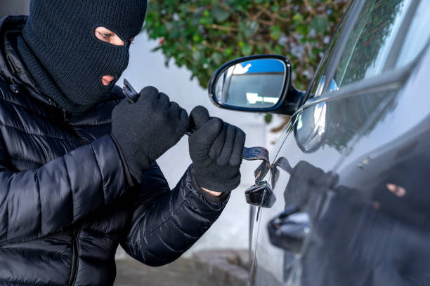 maskierter dieb mit sturmhaube und brechstange, der ein auto stiehlt. - car stealing thief car thief stock-fotos und bilder