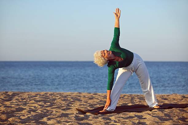 istock Senior woman performing stretches on the beach 187809737